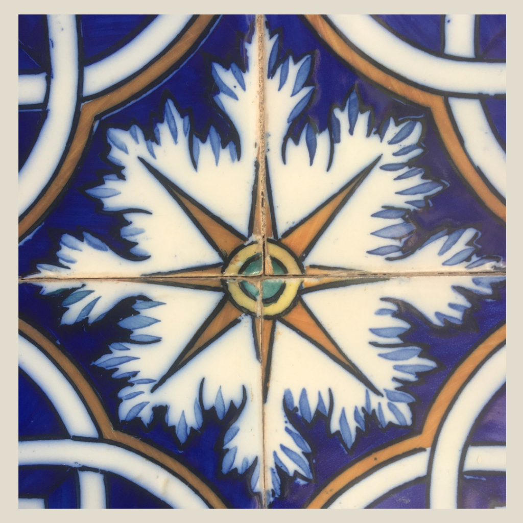 a photograph of a blue gold and cream mosaic tile with a compass rose in the center